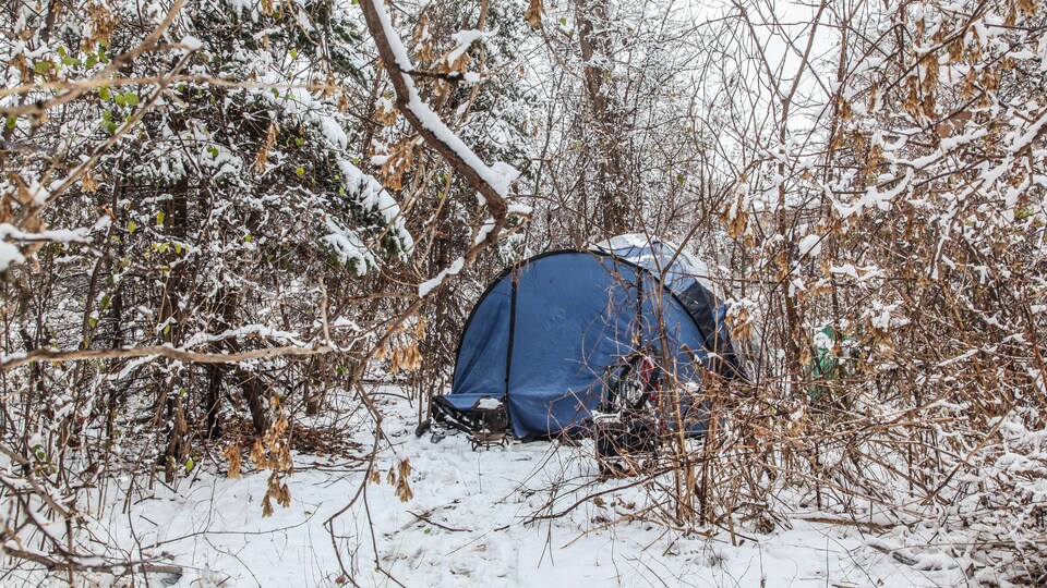 Une tente en hiver dans une forêt.