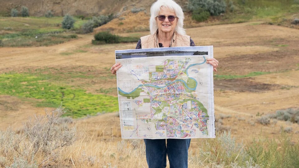 Teresa Vanderhorst tient la carte de Medecine Hat dans ses mains.