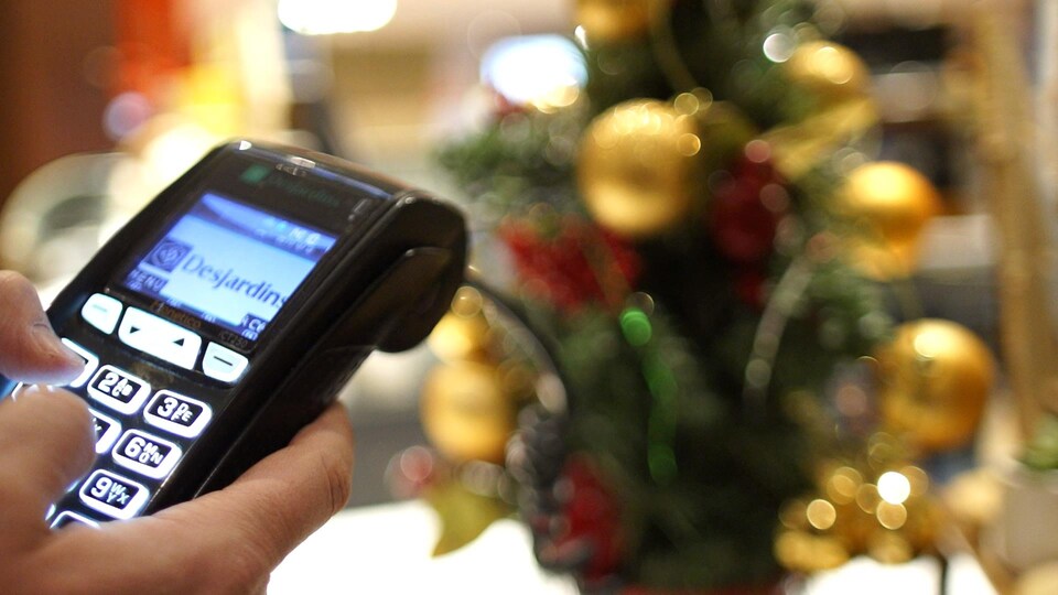 Un terminal de paiement devant un arbre de Noël.
