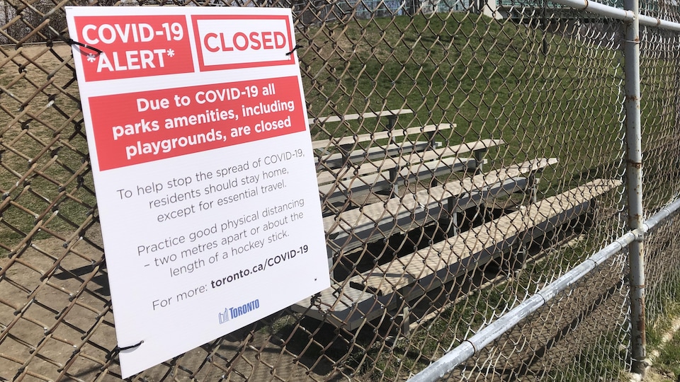 Un avis de fermeture des installations des parcs fixé à la clôture d'un terrain de baseball.