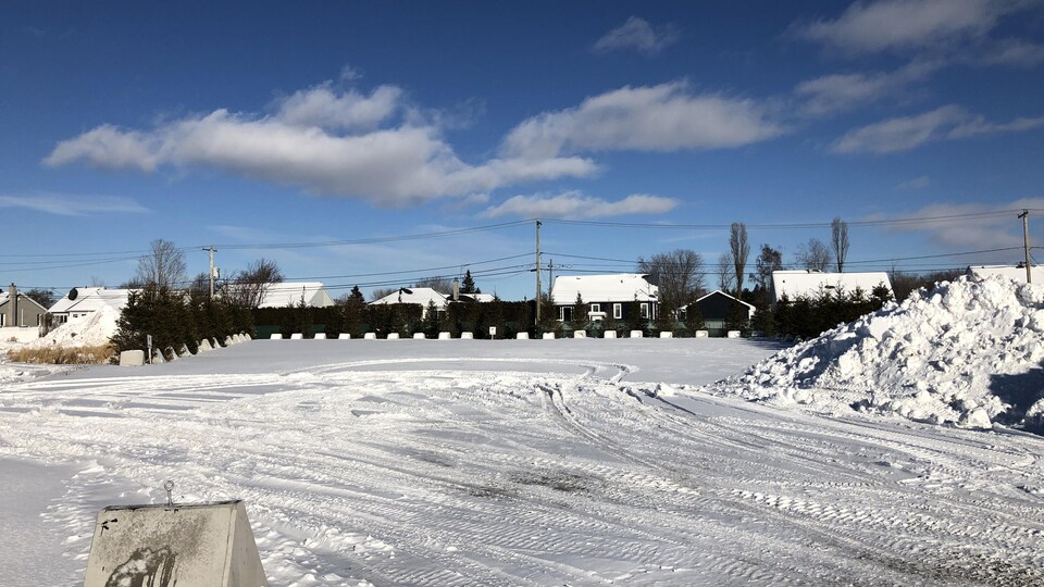 Un terrain vague avec en arrière-plan un quartier résidentiel.