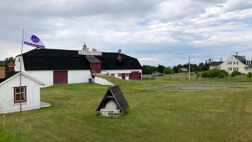 Les terrains acquis par la Première nation malécite de Viger, en juin 2019. On y aperçoit la vieille grange de l'Antiquaire, une maison ancestrale et le drapeau de la Première nation qui y flotte.