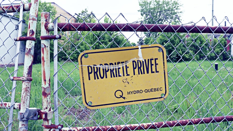 Une clôture de fer sur laquelle est apposée une affiche mentionnant la présence d'un terrain privé et propriété d'Hydro-Québec.