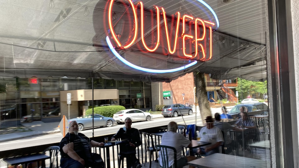 La terrasse d'un bar se reflète dans la vitrine de l'établissement