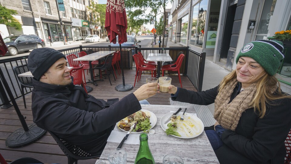 Deux personnes trinquent avec leur verre de café sur la terrasse d'un restaurant.