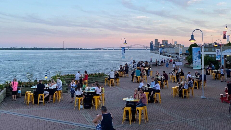 Gens assis à des tables près du fleuve.