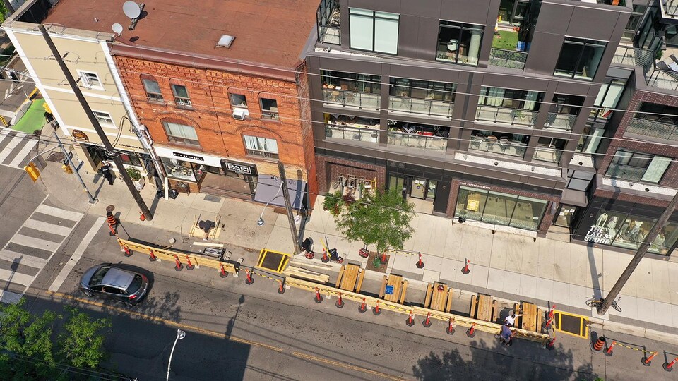 Photo aérienne qui montre l'avenue en plongée. Une partie de l'avenue près du trottoir est fermée à la circulation et des tables ont été dressées sur ses terrasses.