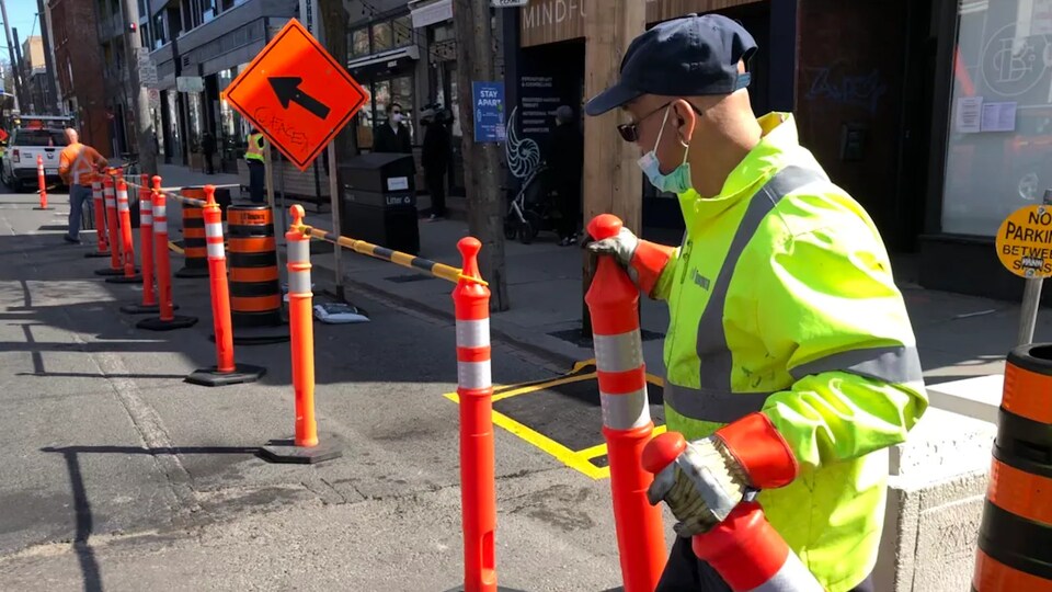 Un employé municipal installe des barrières sur la chaussée.