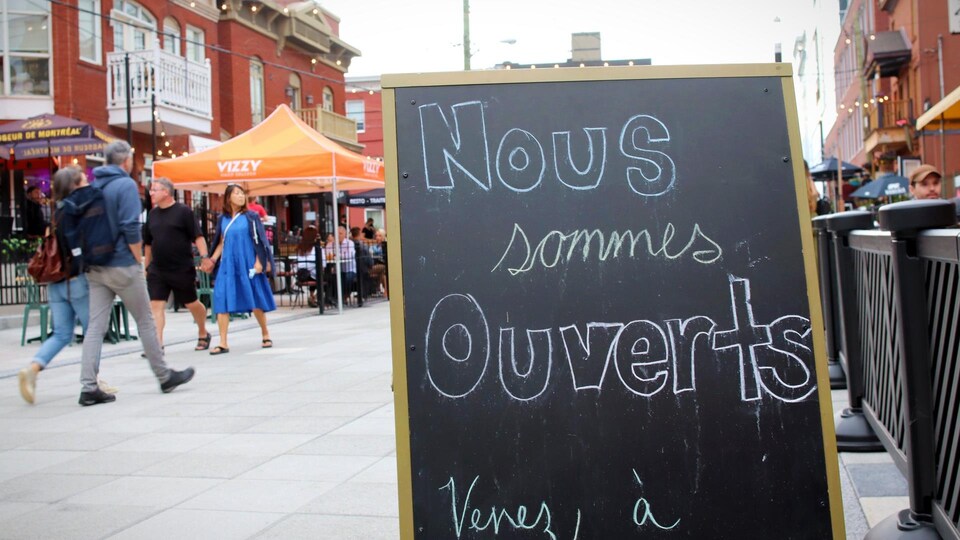 Une pancarte indique que la terrasse d'un restaurant est ouverte.