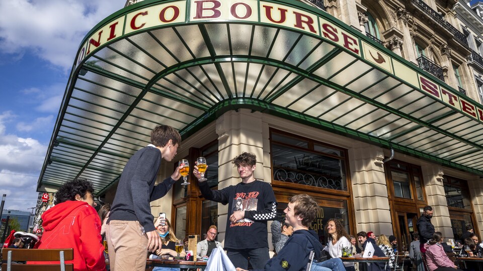 Des jeunes trinquent à la table d'une terrasse.