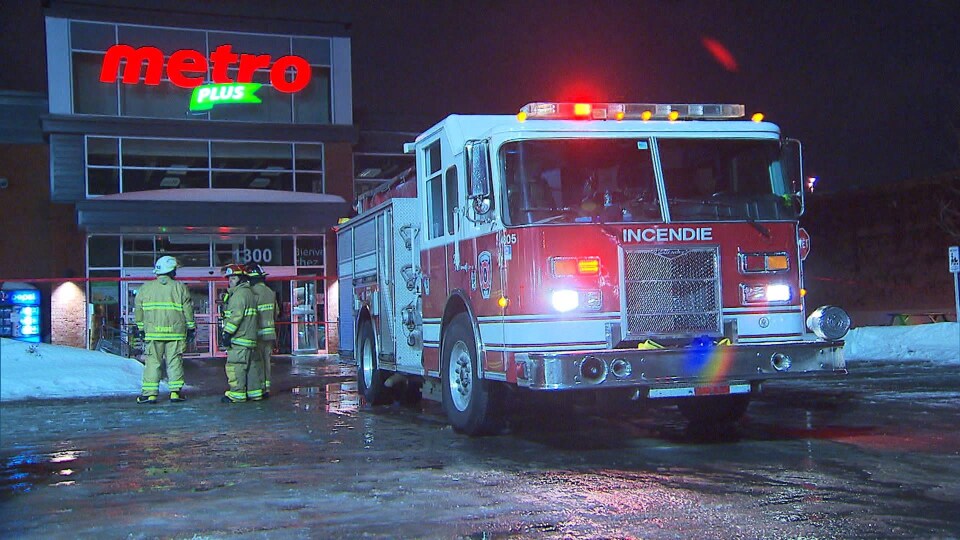 Des pompiers et un camion devant une épicerie
