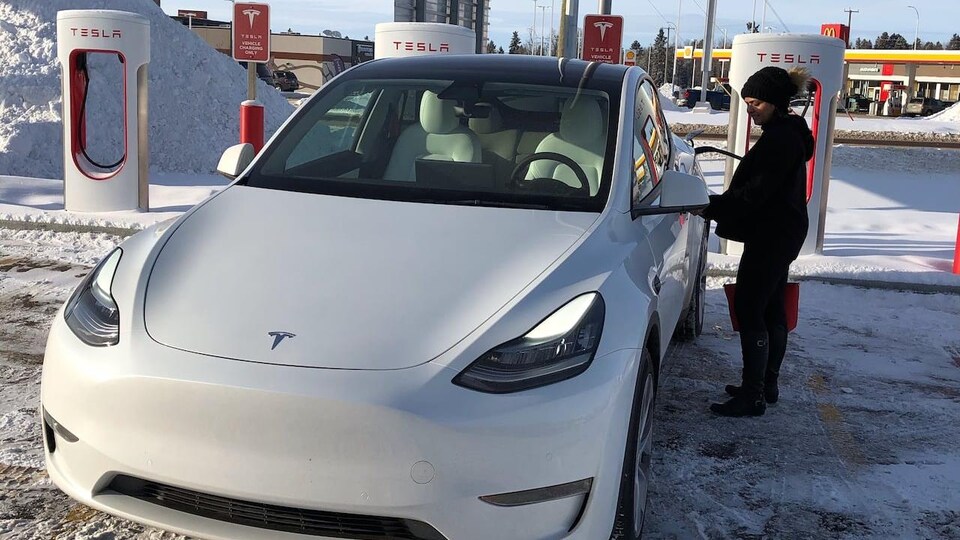 Une femme recharge sa Telsa à une station de recharge en Alberta.