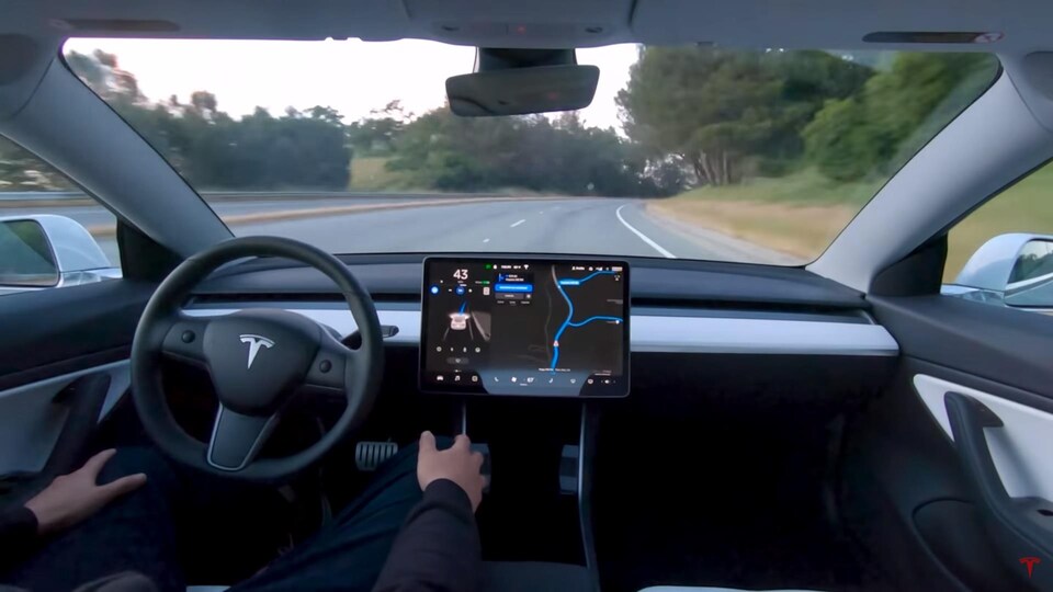 Une vue subjective d'un chauffeur de véhicule Tesla qui n'a pas les mains sur le volant. 