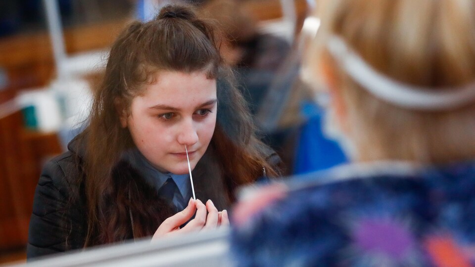 Une adolescente insère un écouvillon dans sa narine.