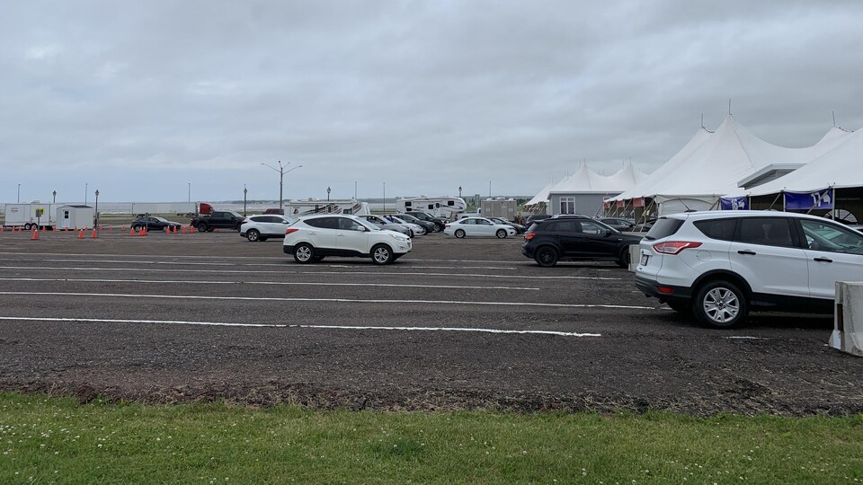 Des voitures arrêtées devant de grandes tentes sur la route.