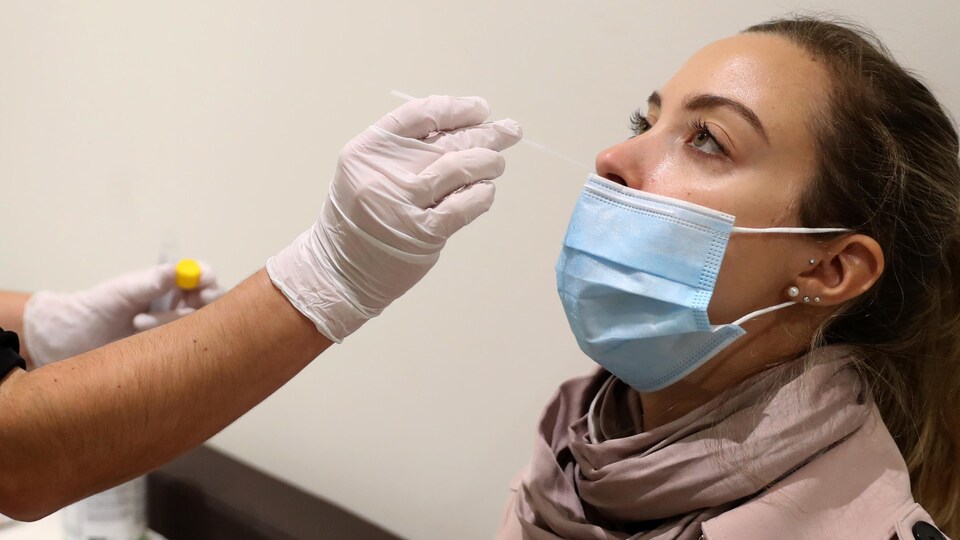 Une infirmière prélève un échantillon de la narine d'une patiente pour un test de dépistage de la COVID-19.