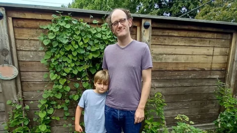 Un homme et un garçon se tiennent debout et regardent la caméra.