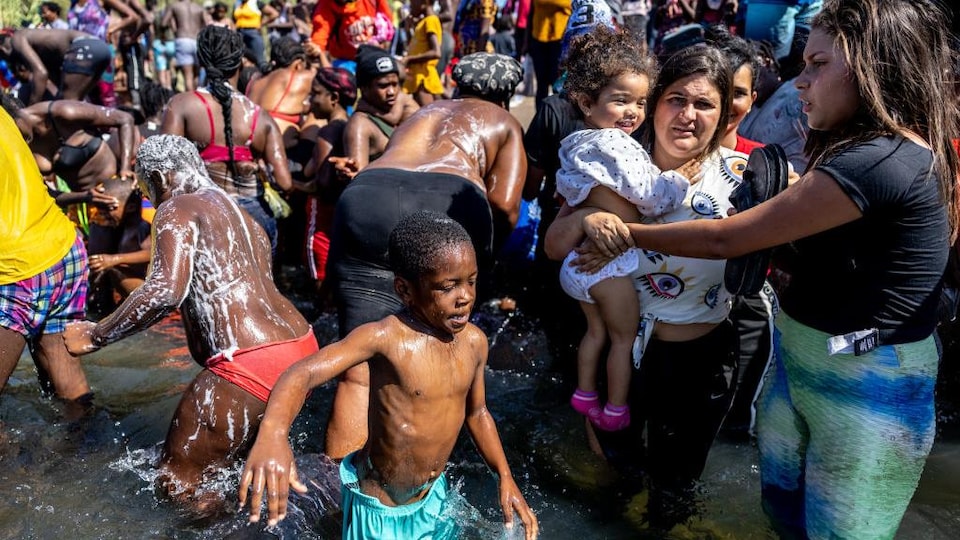Une foule de migrants qui se baignent dans un lac.