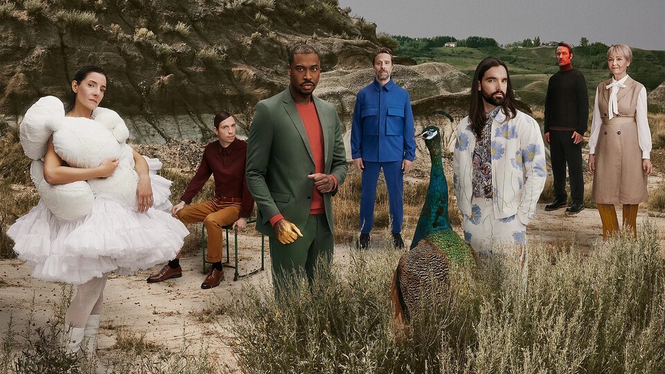 Des personnages en costume sont dans un paysage vallonneux.