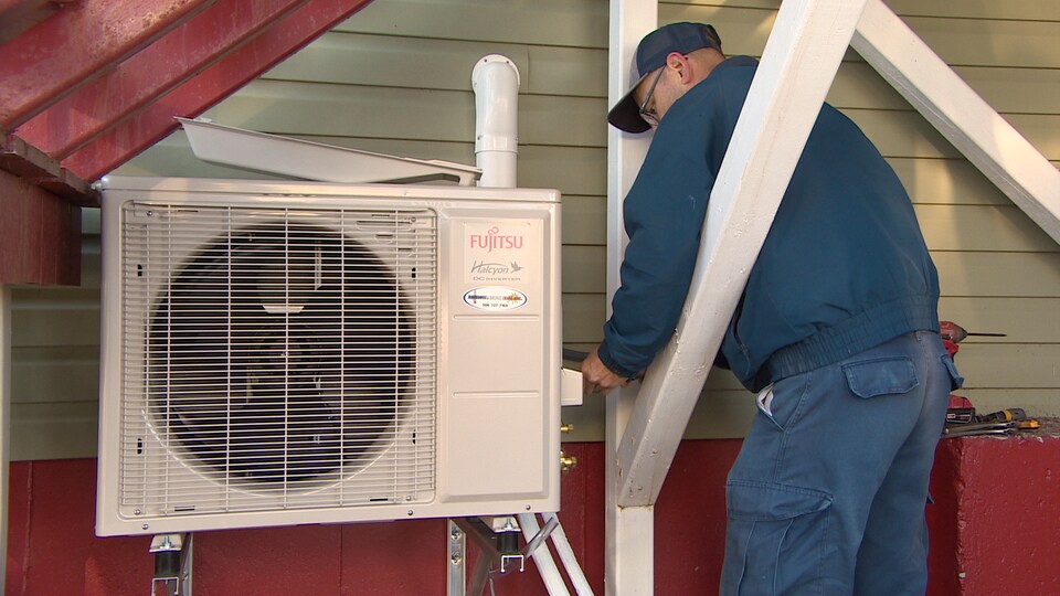 Un installateur ajuste une thermopompe.
