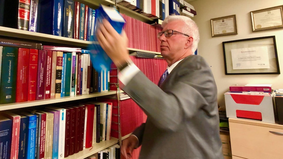 Le professeur de droit constitutionnel Pierre Thibault sort un livre de sa bibliothèque.