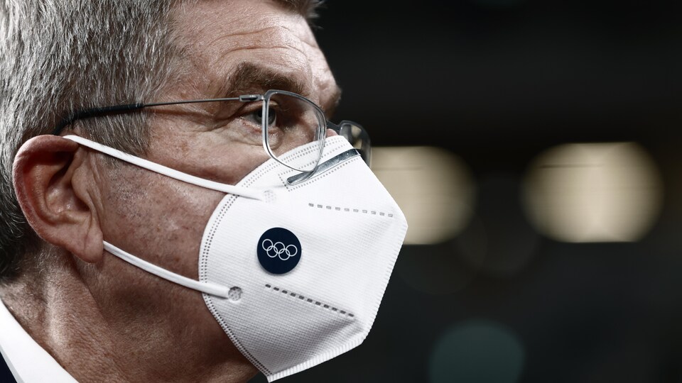 Gros plan du président du Comité international olympique avec un masque portant le logo olympique.