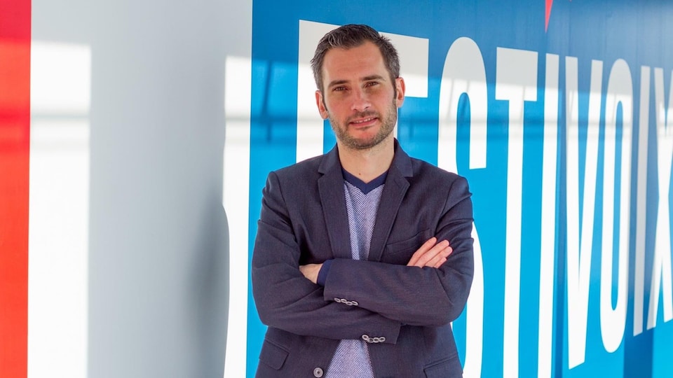 Thomas Grégoire devant une affiche du festivoix.