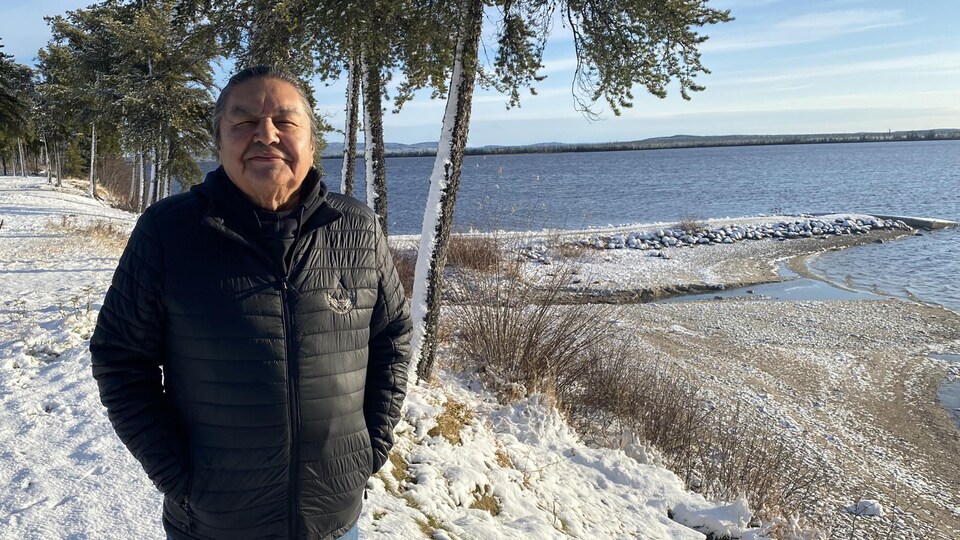 Un homme pose pour la photo sur le bord d'un lac.