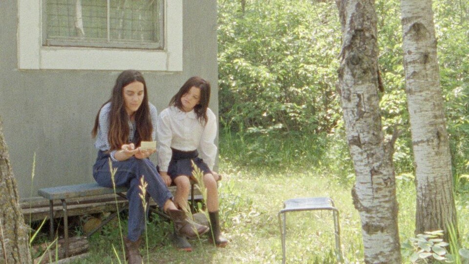 Une femme et une fillette sont assises et lisent une note.