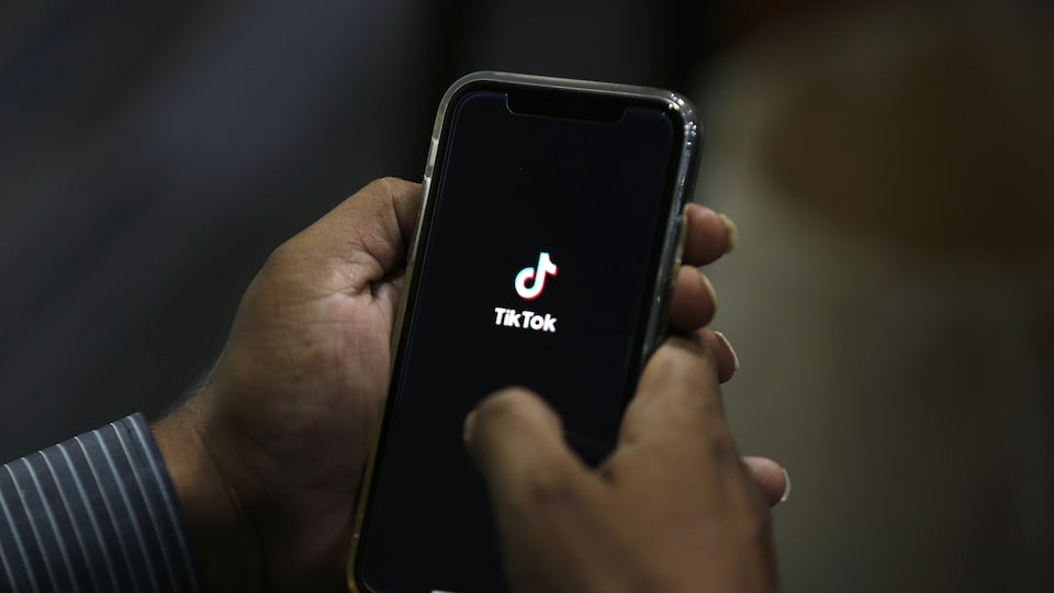 Un homme ouvre l'application Tik Tok sur son téléphone.