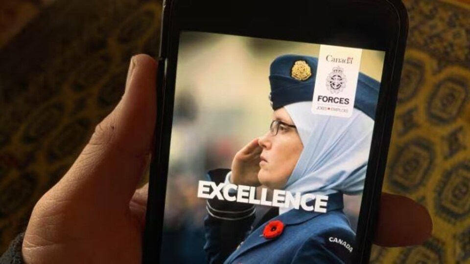 Une publicité des Forces armées montrant une femme portant l'uniforme militaire est vue sur l'écran d'un téléphone intelligent. 