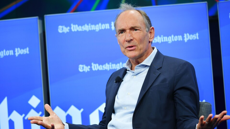 Tim Berners-Lee donne une entrevue au <em>Washington Post</em>, assis sur une chaise posée sur une scène.