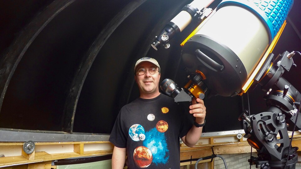 Un homme près d'un gros télescope sous le dôme d'un observatoire.