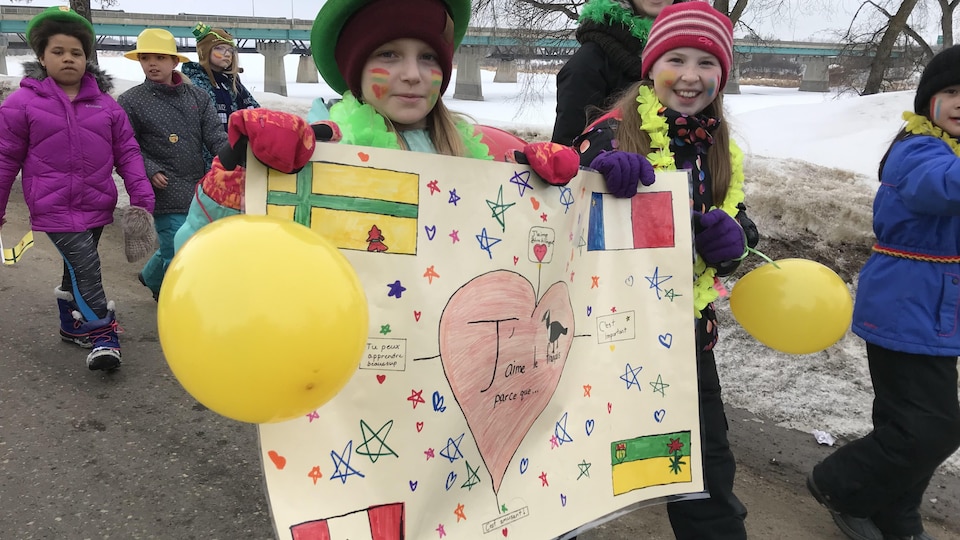 Enfants avec des ballons jaunes et une pancarte sur laquelle ils ont dessiné ce que représente la francophonie pour eux : des drapeaux et un coeur.