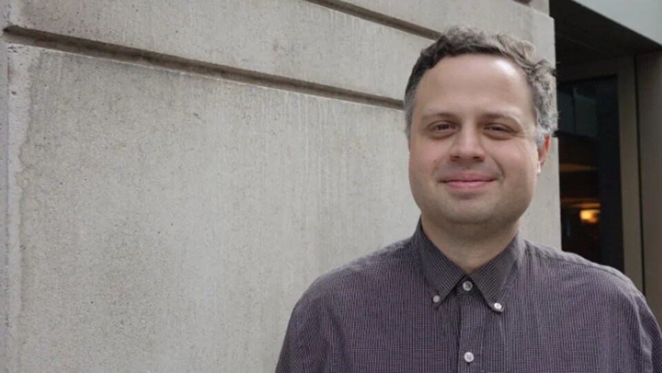 Kevin McIntosh pose pour la caméra devant un mur de béton