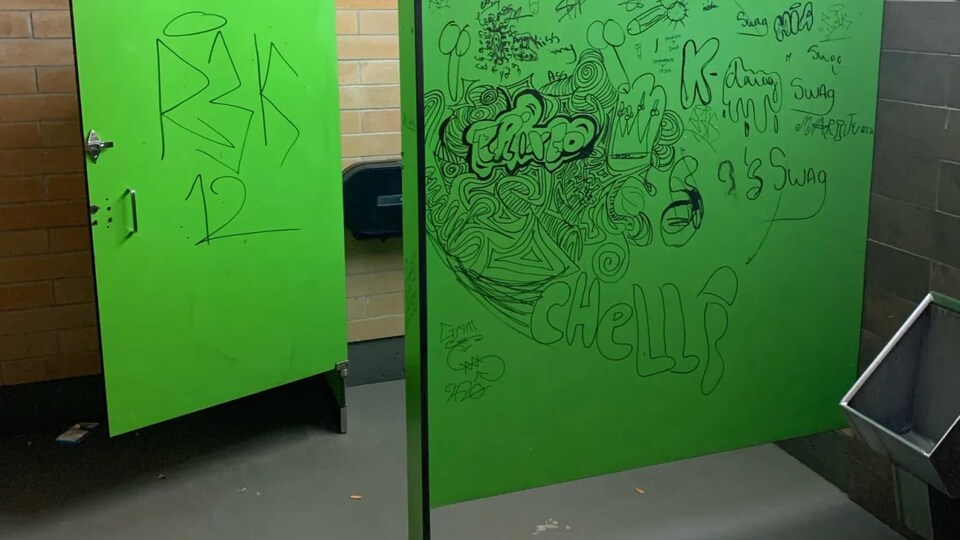 Des graffitis sur des portes de toilettes publiques.