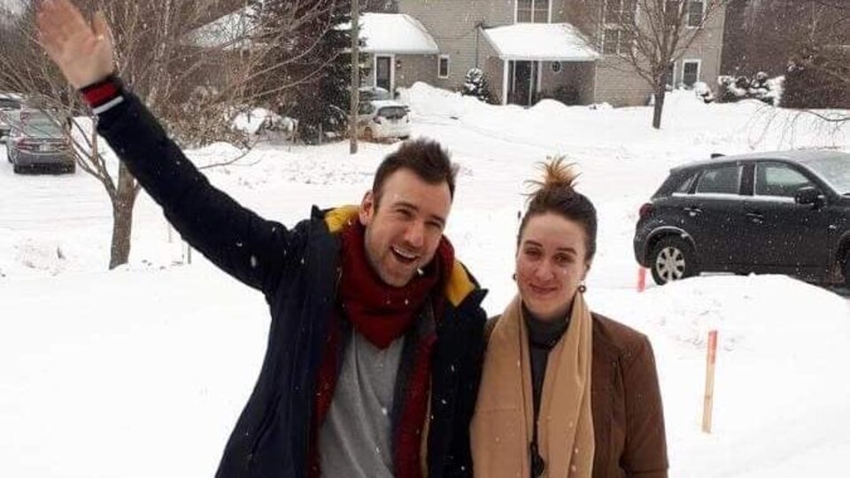 Deux personnes se tiennent dans une allée résidentielle recouverte de neige.