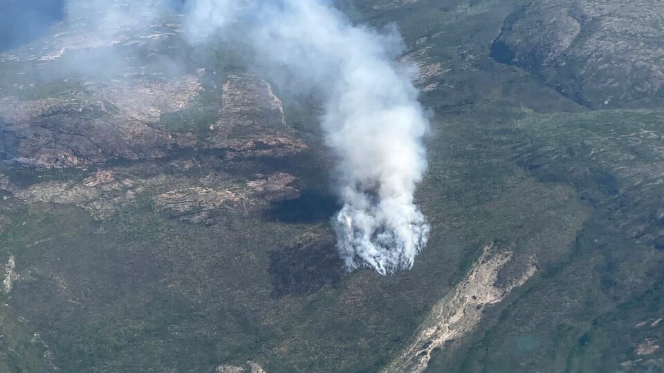 Un feu brûle dans une forêt proche de lacs.