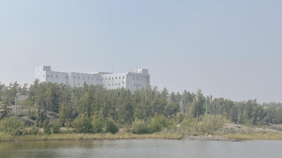 Un bâtiment se dessine sur une colline qui surplombe un lac. La vue est brouillée à cause de la fumée des feux de forêt le 5 juillet 2022.