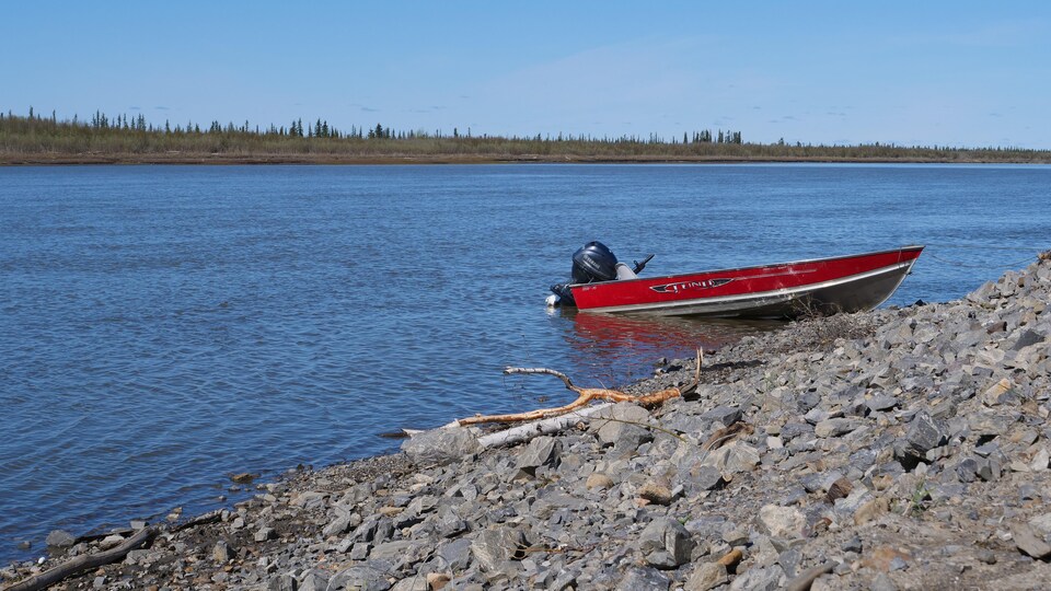 Un bateau accosté sur la grève d'un plan d'eau.