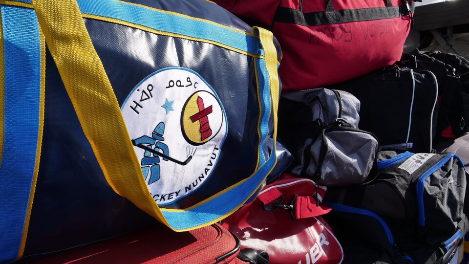 Des sacs de sport sont empilés avec un logo de hockey.