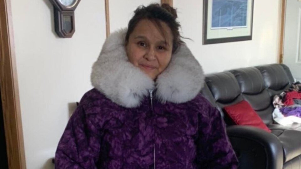 Une femme avec un manteau traditionnel inuvialuit, bordé de fourrure et de broderie, dans un salon.