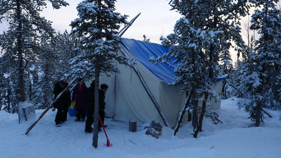 Des enfants sont devant une tente en hiver et des arbres sont recouverts de neige, le 30 novembre 2022, à Yellowknife.