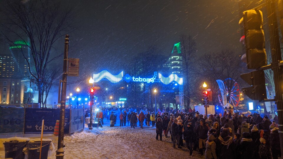 Une foule dans la rue avec des lumières et des flocons de neige.