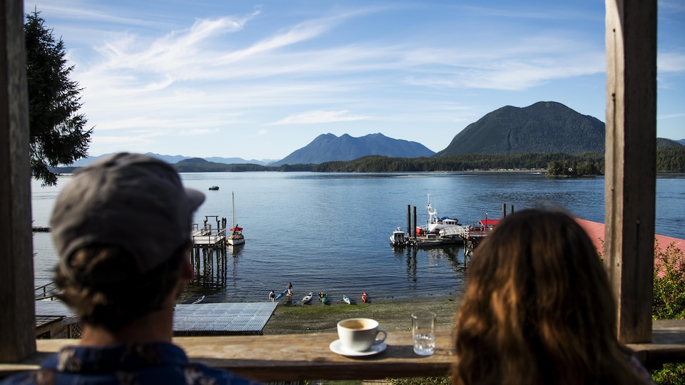 Un homme et une femme de dos assis devant un comptoir qui est au bord de l'eau.