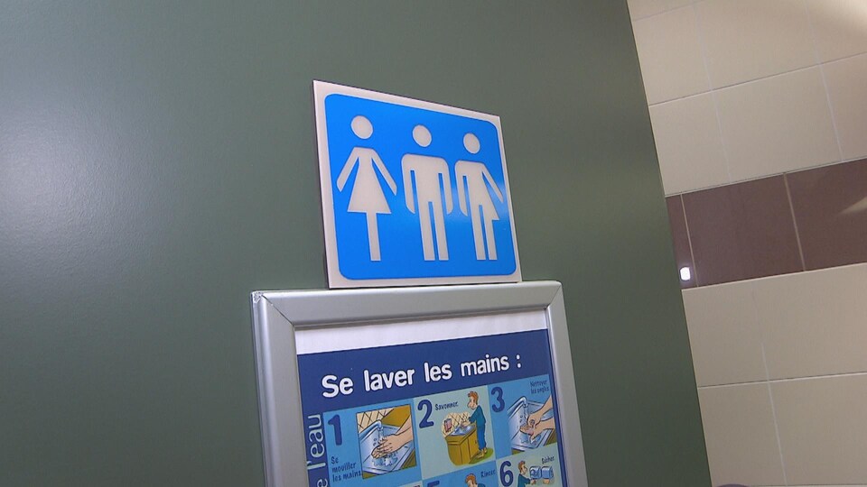 Une affiche bleue sur une porte indique les toilettes.