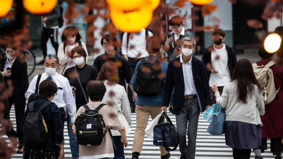Des gens portant des masques se promènent dans la rue.