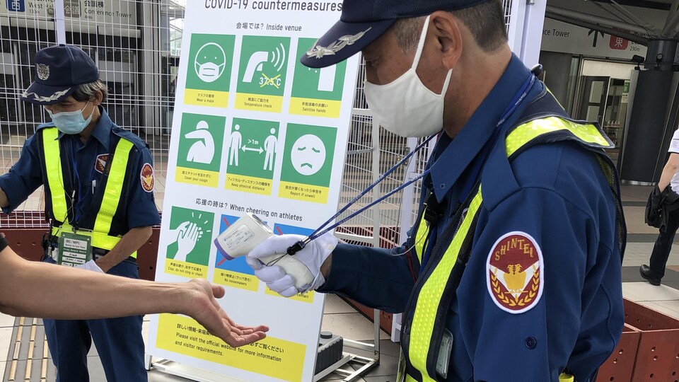 Un technicien pointe un thermomètre vers un bras.