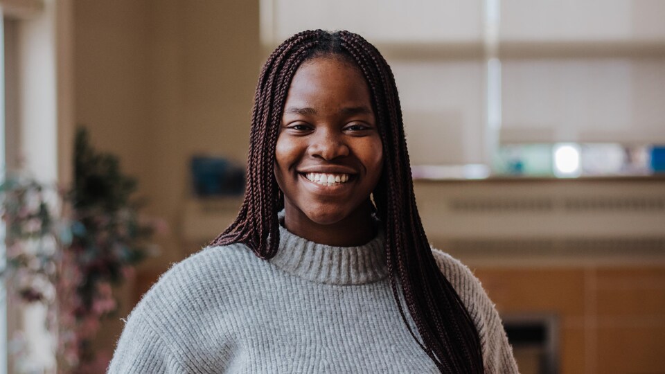 Tolu Oginni pose pour la photo dans une salle de travail étudiante.
