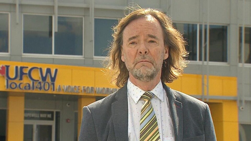 Tom Hesse répond aux questions d'une journaliste devant les locaux de la section locale 401 du syndicat des Travailleurs et travailleuses unis de l'alimentation et du commerce.